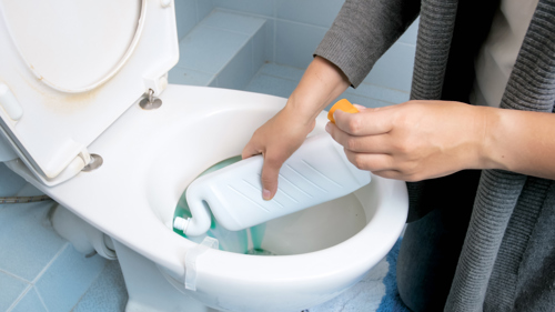 person using diy bathroom cleaner to clean toilet bowl